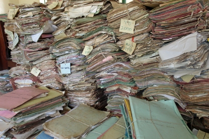 Towers and towers of stacks of tattered paper, very roughly bundled by decade.